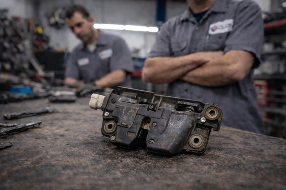 Technician inspecting used tailgate latch