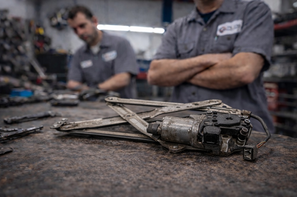 Technician inspecting used tailgate window regulator
