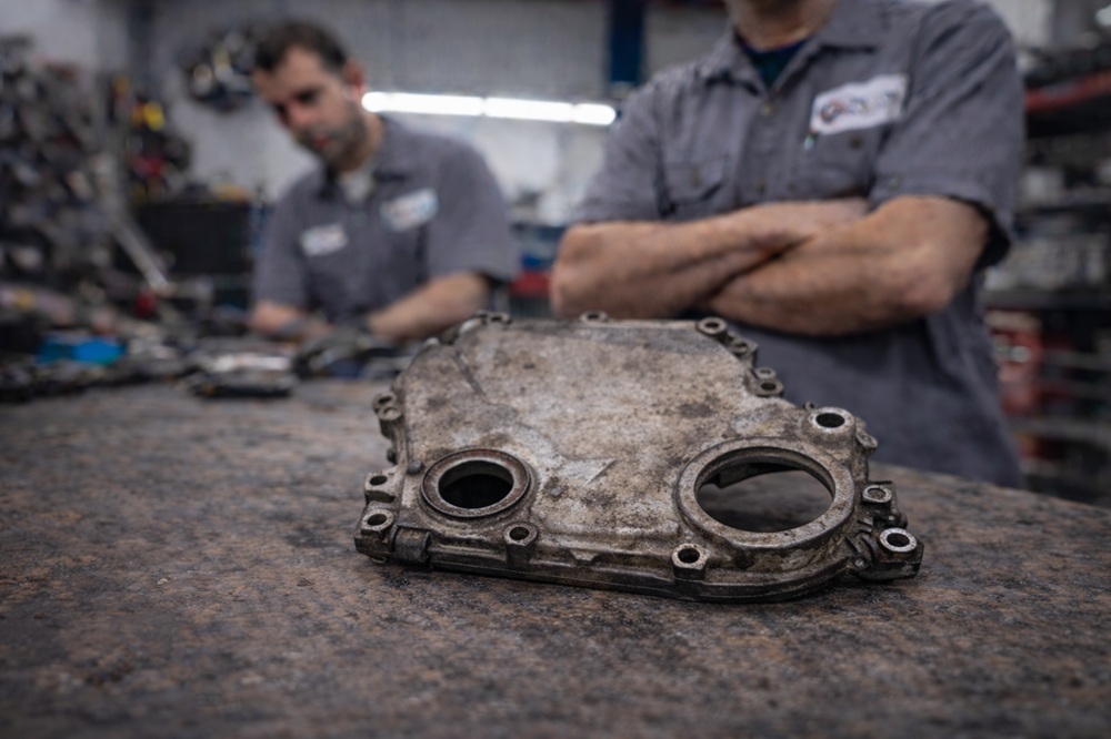 Technician inspecting used engine timing cover