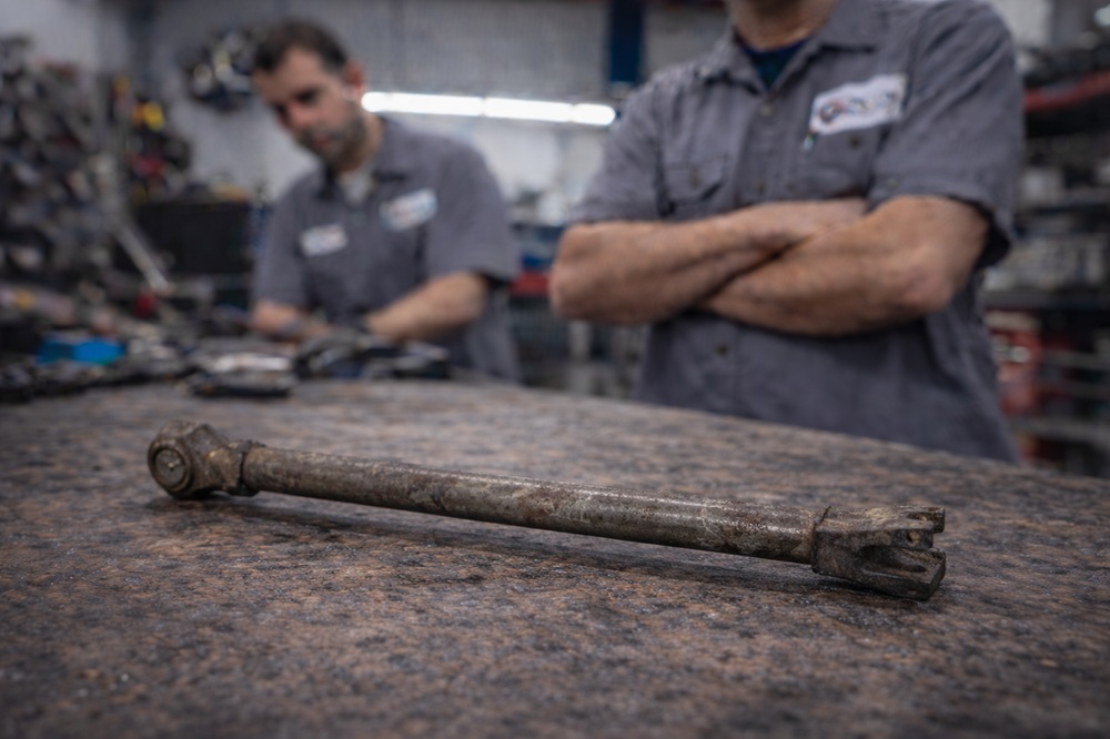 Technician inspecting used torsion bar suspension component